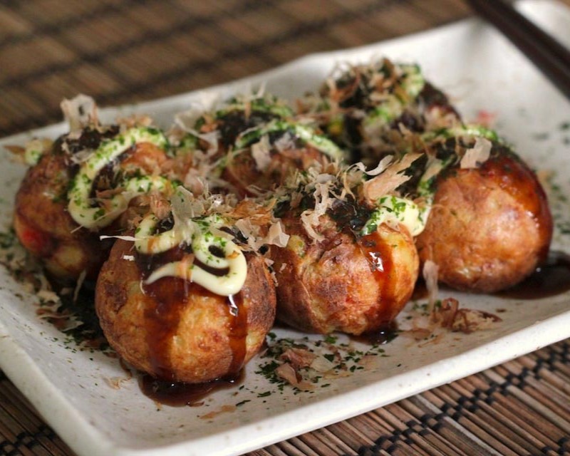 Takoyaki (Japanese: たこ焼き or 蛸焼) is a ball-shaped Japanese snack made of a wheat flour–based batter and cooked in a special molded pan. It is typically filled with minced or diced octopus (tako), tempura scraps (tenkasu), pickled ginger (beni shoga), and green onion (negi).12 The balls are brushed with takoyaki sauce and mayonnaise, and then sprinkled with green laver (aonori) and shavings of dried bonito (katsuobushi).